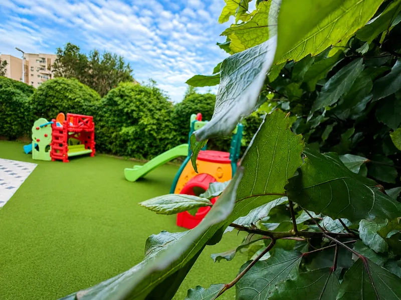 L'aire de jeux extérieure sur gazon, entourée de verdure