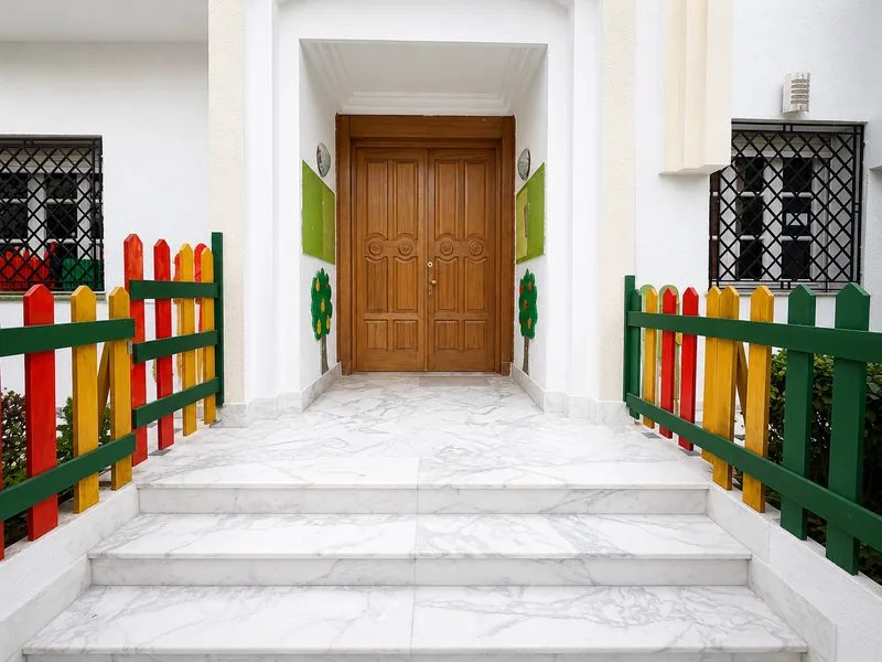 L'entrée de l'école King Child : escalier en marbre et palissade colorée menant à la grande porte en bois